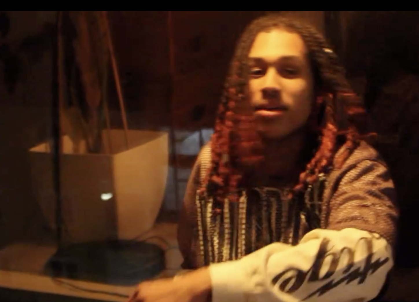 Dappie with red locs in warm lamplight