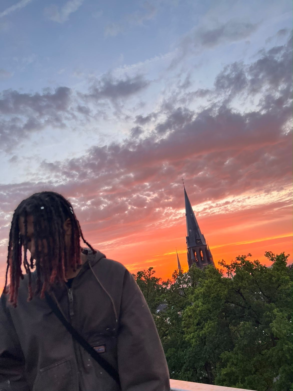 Artist in front of a church spire at burning sunset